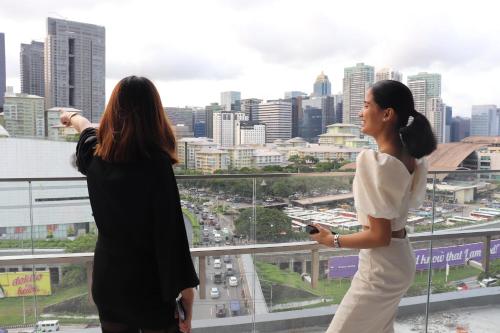 Zwei Frauen stehen auf einem Gebäude mit Blick auf eine Stadt in der Unterkunft Hotel101 - Fort in Manila