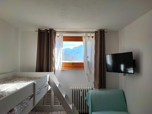a bedroom with a bunk bed with a television and a window at La Casa di Giorgia in Sestriere