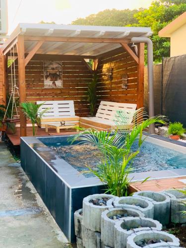 uma piscina com duas cadeiras e uma pérgola em Villa de 2 chambres avec vue sur la ville piscine privee et jardin clos a Le Lamentin em Le Lamentin