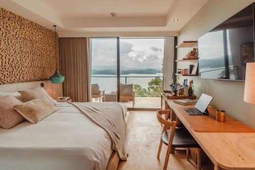 a bedroom with a bed and a desk with a laptop at The Brown, Guatape in Guatapé