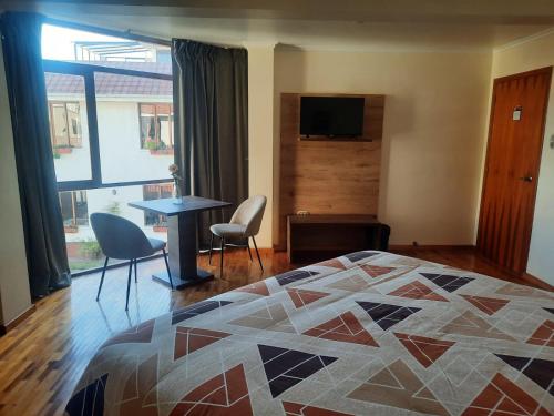1 dormitorio con 1 cama, mesa y sillas en Hotel Rincon Aleman, en Riobamba