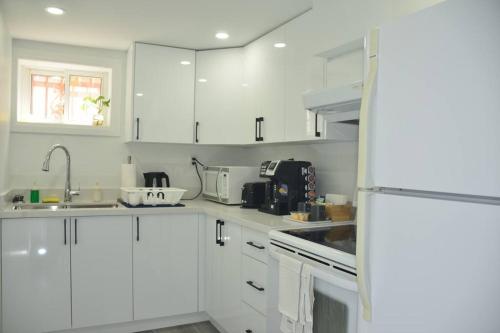 uma cozinha branca com armários brancos e um lavatório em Entire Basement - 5 Guests 2 Bedrooms 3 Beds em Toronto