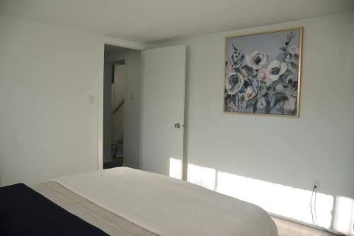 a white bedroom with a painting on the wall at Entire Basement - 5 Guests 2 Bedrooms 3 Beds in Toronto