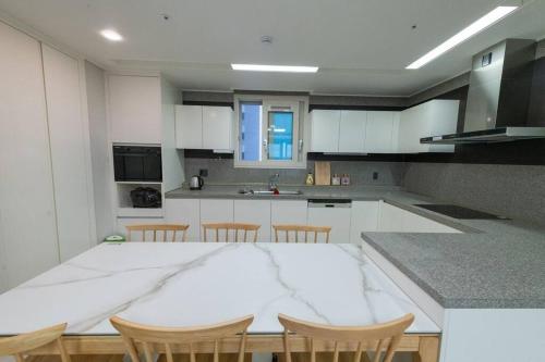 uma cozinha com uma grande mesa branca e cadeiras em Kangdong K Residence em Ulsan