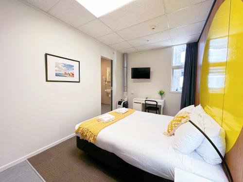 a bedroom with a large bed with a yellow headboard at Wellington Hotel in Wellington