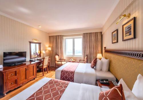 a hotel room with two beds and a flat screen tv at Hotel Grand Saigon in Ho Chi Minh City