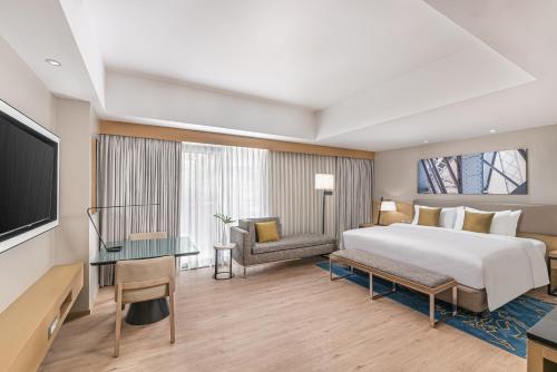 um quarto de hotel com uma cama e uma televisão em Seda Manila Bay em Manila