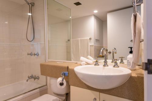 a bathroom with a sink and a shower and a toilet at Story Bridge view apartment with parking and pool in Brisbane