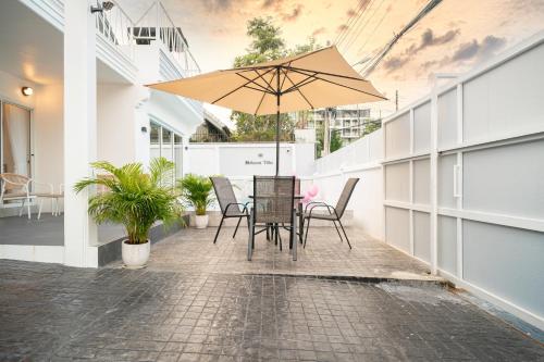 a patio with a table and chairs and an umbrella at Mohana Pool villa 4 bedrooms near walking street in Pattaya South
