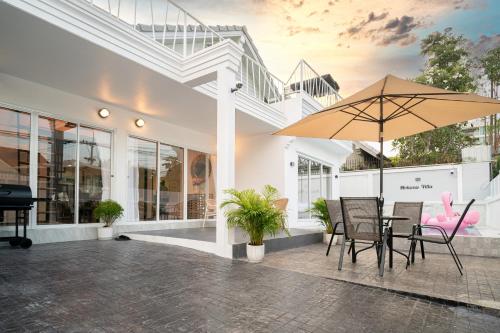 a patio with a table and chairs and an umbrella at Mohana Pool villa 4 bedrooms near walking street in Pattaya South
