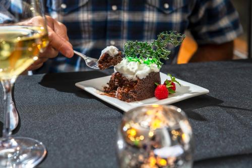 a person eating a dessert on a plate with a drink at Sheridan House Inn- Adult Only Accommodation in Williams
