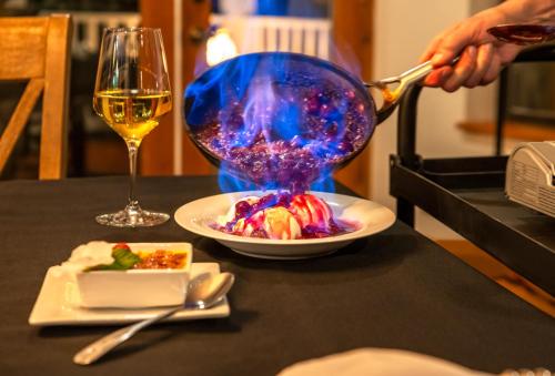 a person is serving a plate of food and a glass of wine at Sheridan House Inn- Adult Only Accommodation in Williams