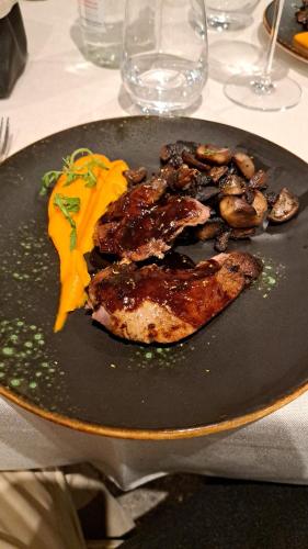 a plate of food with meat and mushrooms on a table at L'Auberge du Mazet in Lodève