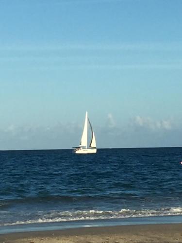 a sail boat in the ocean with a beach at Mermaid's Lighthouse in West Palm Beach