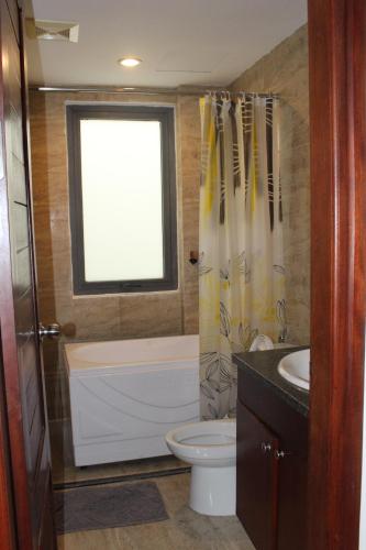 a bathroom with a tub and a toilet and a window at Davidduc's Duplex Apartment Xom Chua (5F) in Hanoi