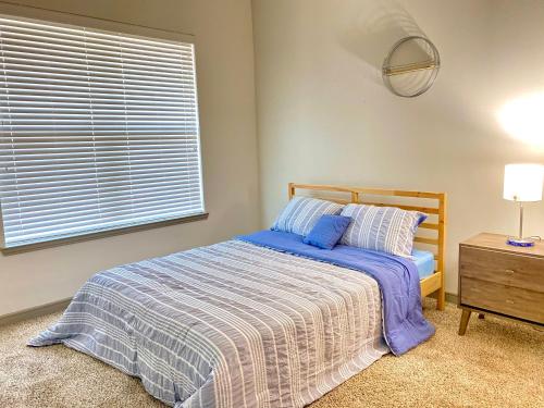 a bedroom with a bed with a blue comforter and a window at The Baobab - Addison in Dallas