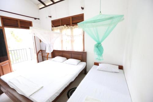 two beds in a room with a window at Sinharaja River Face holiday in Nelluwa