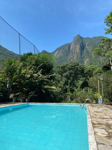 een zwembad met bergen op de achtergrond bij Sítio com piscina e churrasqueira in Guapimirim