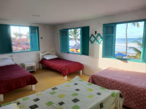 um quarto com duas camas e janelas com a praia em Privê Sol e Mar em Cabo de Santo Agostinho