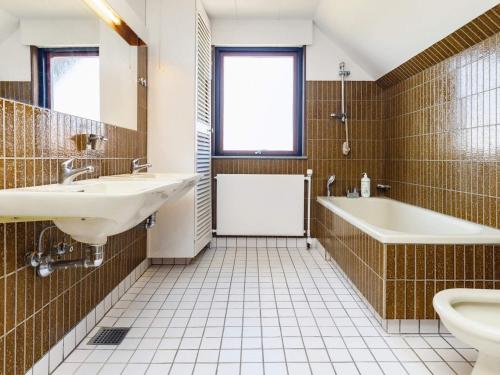 łazienka z 2 umywalkami, wanną i toaletą w obiekcie Holiday home Assens IX w mieście Assens