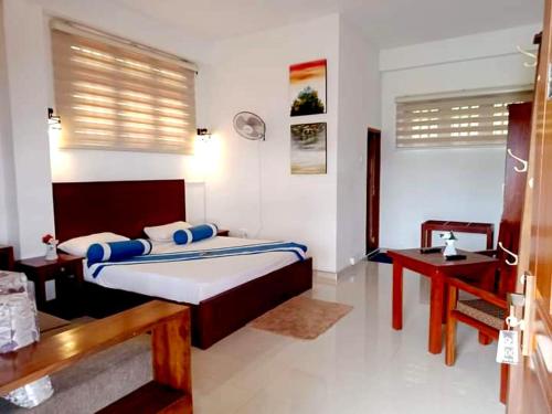 een slaapkamer met een groot bed en een bureau bij Nature First Hotel in Nuwara Eliya