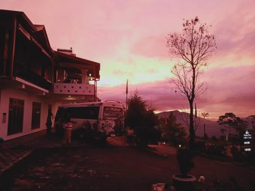 a bus parked in front of a building with a sunset at Nature First Hotel in Nuwara Eliya