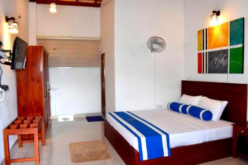 a bedroom with a bed and a chair and a television at Nature First Hotel in Nuwara Eliya