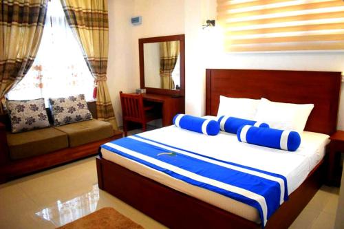 a bedroom with a bed with blue and white pillows at Nature First Hotel in Nuwara Eliya