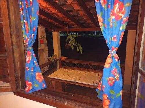 a window with blue curtains with flowers on it at Chalé Ebenézer in Eldorado