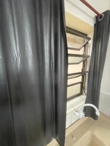 uma cortina preta num quarto com uma prateleira em 02 Doutor hostel 800 mts da praia no Guarujá