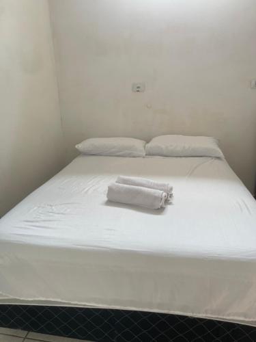 Una cama blanca con dos toallas blancas. en 02 Doutor hostel 800 mts da praia en Guarujá