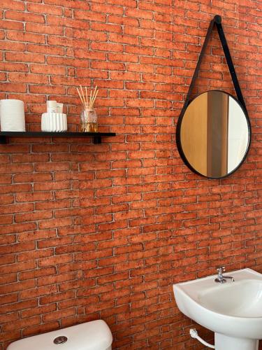 a red brick wall with a mirror and a sink at Condomínio Indianopolis a 1,4km do North Shopping in Caruaru