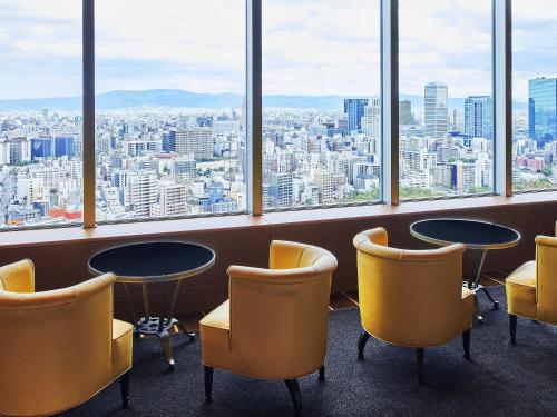 a room with two tables and chairs and windows at Imperial Hotel Osaka in Osaka