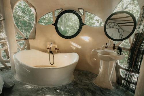 a bathroom with a tub and a mirror and a sink at Ikalar in Akumal