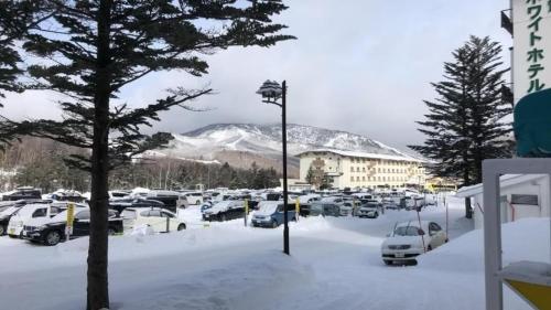 a parking lot covered in snow with a snow covered mountain at ホテルサンモリッツ志賀 in Shiga Kogen