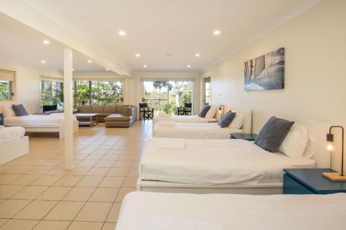 a large room with three beds and a couch at The Treehouse Vincentia in Vincentia