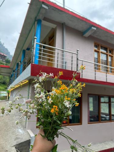a person holding a bouquet of flowers in front of a house at WildFlower in Tosh