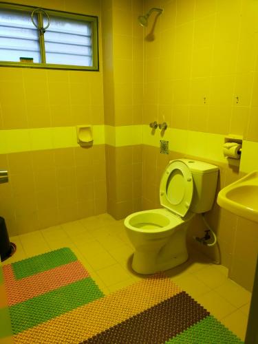 a yellow bathroom with a toilet and a sink at R2L5Y Room 2 in Bentong
