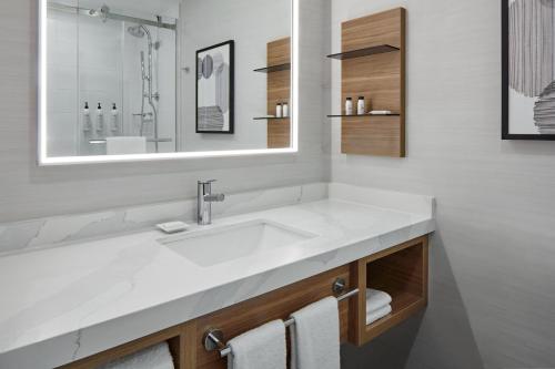 een badkamer met een witte wastafel en een spiegel bij Delta Hotels by Marriott Toronto Markham in Markham