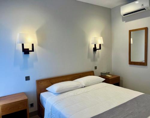 努沙杜瓦的住宿－Charlie Guest House，卧室配有一张床,墙上有两盏灯
