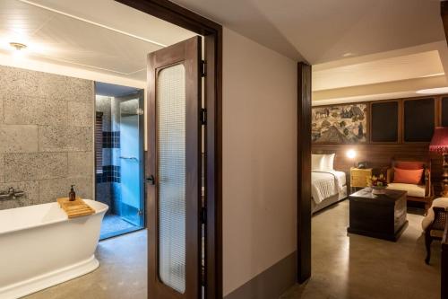 een badkamer met een bad en een slaapkamer bij Payaa Hotel in Pattaya