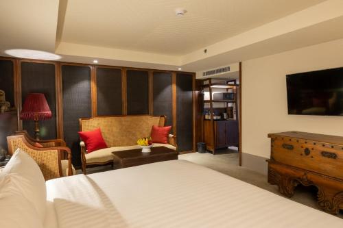a bedroom with a bed and a chair and a table at Payaa Hotel in Pattaya