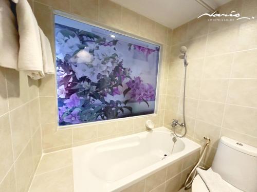 a bathroom with a tub and a flower painting on the wall at Naris Art Hotel in Pattaya South