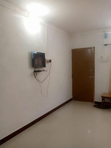 a room with a tv on a wall with a door at Holiday Tourisms Group of Homestay Rooms Scuba Diving Boating Watersports-Tarkarli-Devbag Beach in Bhogwe