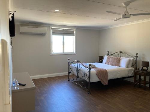 1 dormitorio con 1 cama con sábanas blancas y ventana en The Wooly Guesthouse, en Wagin