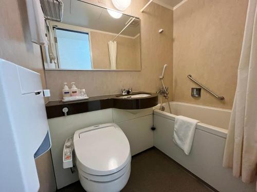 a bathroom with a toilet and a sink and a mirror at Shinseto Station Hotel in Seto