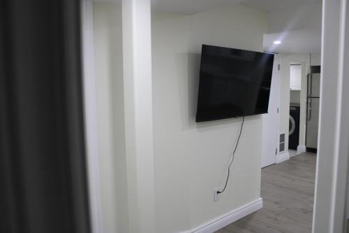 telewizor z płaskim ekranem wiszący na białej ścianie w obiekcie Comfyhome w mieście Vaughan