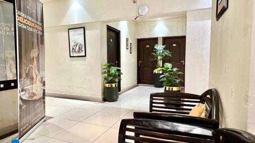 un pasillo con sillas y plantas en un edificio en Royal Inn Hotel, en Karachi