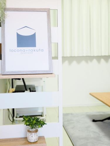 a picture frame on a shelf with a plant at locona +rakuta in Hyuga