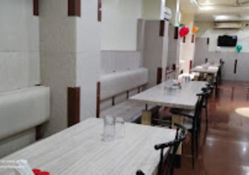 ein Zimmer mit Tischen und Stühlen in einem Zimmer in der Unterkunft Hotel Premier - Hotel in Saket Society Bhusawal in Bhusāwal